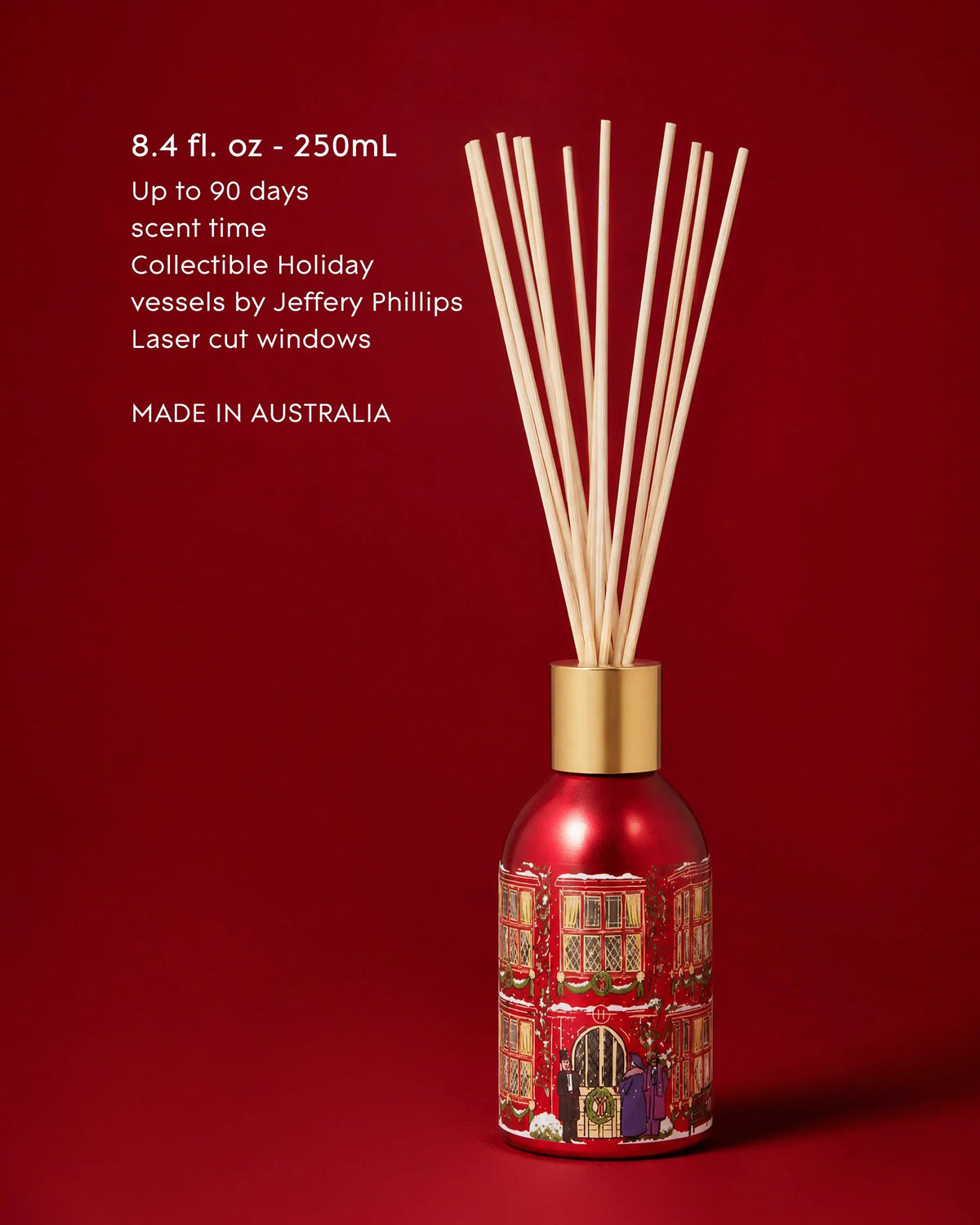 A red reed diffuser bottle with laser-cut holiday window detailing and natural reed sticks
