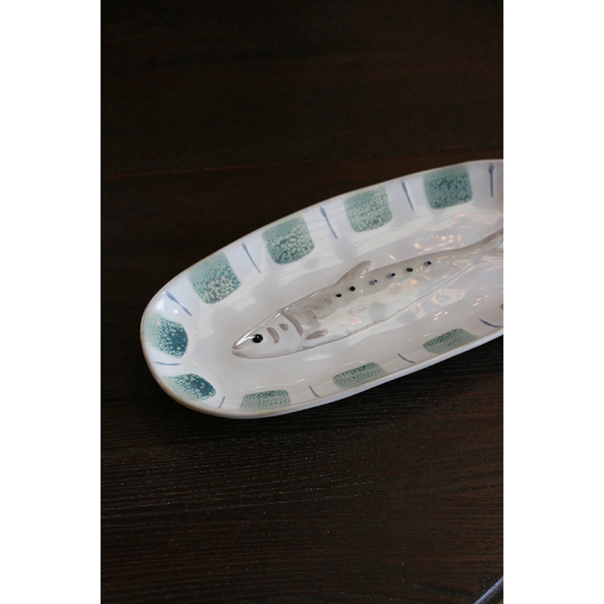 Sushi Plate Fish An oval ceramic serving platter featuring a molded fish in the center and a border of textured sage green squares with blue accents