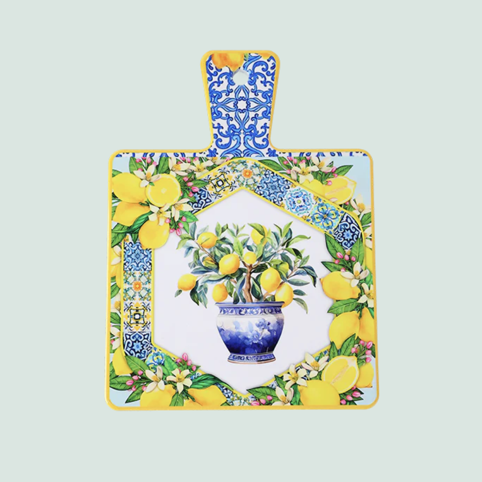 Carbea Imports Decorative trivet with handle, featuring a vibrant lemon design. Perfect for protecting surfaces from hot pots and dishes while adding a fresh, cheerful touch to your kitchen décor. Decorative cutting board with floral and lemon design 